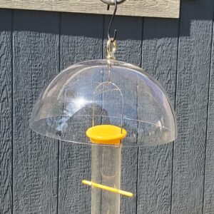 close up of upside down goldfinch feeder under clear hanging baffle